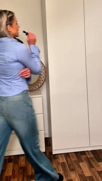 Világoskék csíkos ing, laza fazonú világoskék farmernadrággal párosítva. A háttérben egy fehér szekrény és egy kör alakú dísztükör látható.