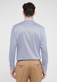 Lichtblauw gemusterd overhemd met lange mouwen, een spread collar, knoopmanchetten en een gladde, geweven textuur. Gecombineerd met beige geklede broek.