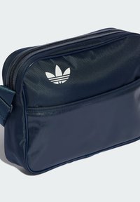 Tamsiai mėlynas sintetinis maišas su lygiu paviršiumi, užtraukiama kišenė ir balta Adidas logotipas. Yra reguliuojama dirželis patogiam nešimui.