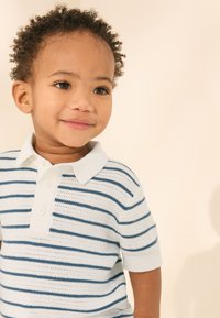 Randig kortärmad pikétröja i mjukt vitt tyg med blå horisontella ränder, med klassisk krage och tre-knappars knäppning.