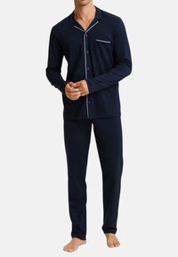 Ensemble de pyjama en coton bleu marine avec manches longues, devant à boutons, passepoil blanc sur le col et la poche, et pantalon assorti.