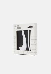 Návrh na zápästnú taštičku Nike Cortez v čiernej farbe s bielymi akcentmi. Má zakrivené švy a hladkú textúru. Balené v minimalistickom dizajne krabice.