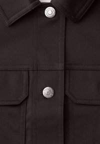 Mørkebrun jakke foran med krave, to klaplommer og sølvfarvede trykknapper med indgraveret "Street One".