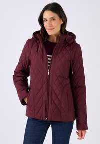 Giacca trapuntata borgogna con cappuccio, chiusura con zip e due tasche laterali. Presenta motivi diagonali e una consistenza morbida.