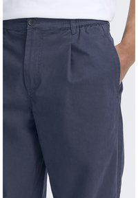 Granatowe spodnie o luźnym kroju, z elastycznym pasem, bocznymi kieszeniami i gładkim materiałem z mieszanki bawełny.