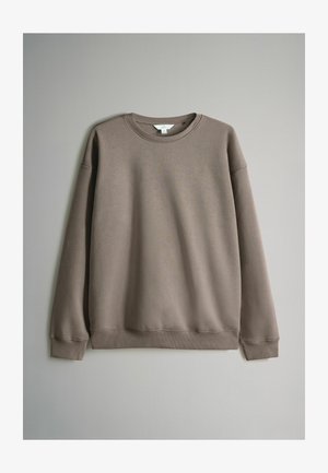 Felpa marrone con colletto tondo, polsini e orlo a coste. Il materiale sembra morbido e tessurizzato, con spalle basse e una vestibilità rilassata.