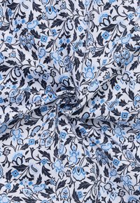 Weißer Stoff mit schwarzen und hellblauen Blumen- und Paisleymustern, in der Mitte gerafft und gedreht.
