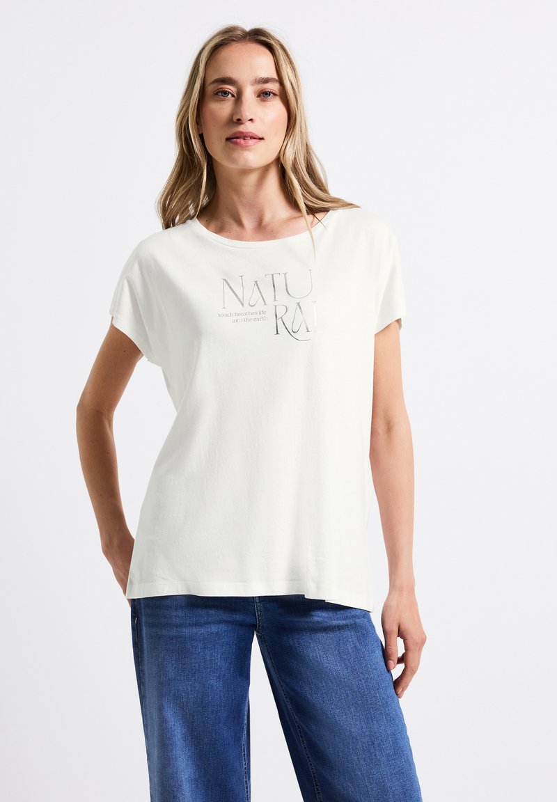 Camiseta de algodón blanca de manga corta, con un diseño impreso que dice "NATURAL" en gris. La tela tiene una textura suave.