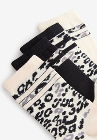 Drei Paar Knöchelsocken mit schwarz-weißem Leopardenmuster, einfarbig schwarz und weiß mit schwarzen und grauen Tiermustern.