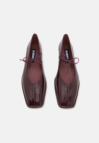 Bordeauxfarbene Lederschuhe mit quadratischem Zehendesign, ausgestattet mit einer glatten Textur und gebundenen Schnürsenkeln in einer kontrastierenden Farbe. Das Innenfutter ist in passendem Bordeaux.