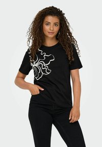 Sorte bomulds t-shirt med et hvidt abstrakt blomsterdesign på venstre side, der har korte ærmer og en afslappet pasform.
