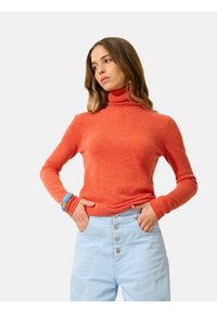 Roter Rollkragenpullover aus weichem, strukturiertem Material, figurbetontes Design mit langen Ärmeln, kombiniert mit hellblauen Jeans mit hoher Taille.