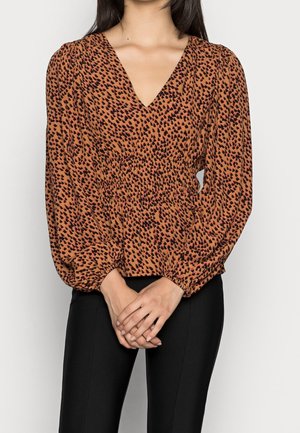 Brun blus med orange och svart leopardmönster, V-ringning, rynkad midja och voluminösa långa ärmar; kombinerad med åtsittande svarta byxor.