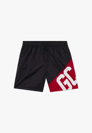 Zwarte zwembroek met een rood diagonaal paneel op het rechterbeen, met grote witte letters "GC" en een elastische tailleband met trekkoord.
