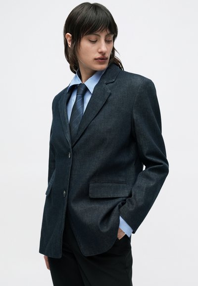 Μπλε σκούρο τζιν σακάκι με έντονα πέτα, δύο μπροστινές τσέπες, κλείσιμο με ένα κουμπί και μακριά μανίκια. Υπέροχη υφασμάτινη υφή με πουκάμισο από κάτω.