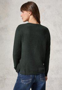 Dunkelgrüner Pullover mit Rundhalsausschnitt und langen Ärmeln, aus weichem, strukturiertem Material gefertigt. Verfügt über eine lockere Passform und seitliche Schlitze am Saum.
