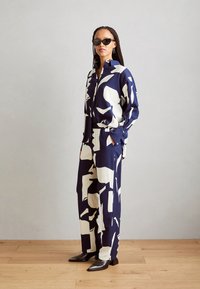 Two-piece outfit made of soft fabric, featuring a navy background with large white abstract shapes, paired with black ankle boots.