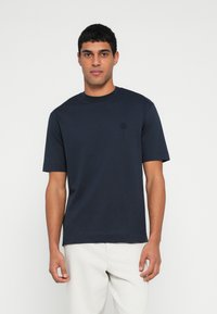 Granatowy t-shirt z krótkim rękawem wykonany z miękkiego materiału, z okrągłym dekoltem i małym logo na piersi.