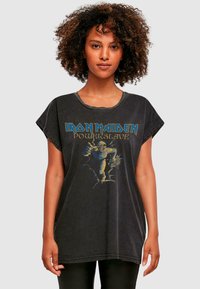 Sort oversized T-shirt med et grafisk print af en mumie, der bryder igennem klipper. Lavet af bomuldsstof med en afslappet pasform og opsmøgede ærmer.