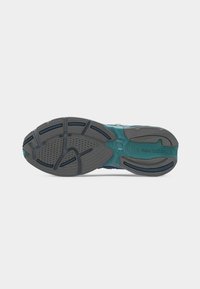Εξωτερική σόλα παπουτσιού τρεξίματος New Balance σε γκρι και τιρκουάζ, με υφασμένα σχέδια πέλματος και εμφανές όνομα της μάρκας στη φτέρνα.
