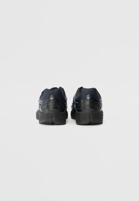 Baskets de sport noires avec un upper en mesh texturé, un col rembourré et une semelle en caoutchouc. Présente des accents bleus et un design de talon strié.