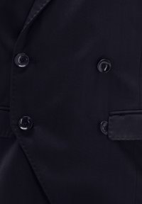 Schwarzer doppelt-knopfbarer Blazer mit glänzenden Knöpfen, glattem Stoffstrick und strukturierten Revers. Mit seitlichem Taschen-Detail.