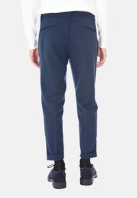 Pantaloni tapered blu navy in tessuto testurizzato, con vita elasticizzata e orli arrotolati. Include due tasche posteriori con cuciture sottili.