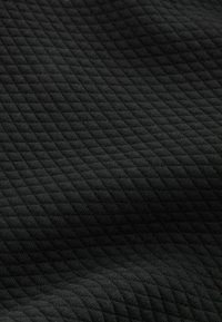 Schwarzer Stoff mit einem gesteppten Muster und erhöhten Rautenformen, das eine weiche Textur und eine gleichmäßige Farbe aufweist.