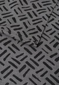 Grijs stof met een repetitief zwart abstract patroon van verticale en diagonale lijnen. De textuur is soepel en geweven.