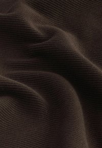 Hladká hnědá tkanina s měkkým, texturovaným povrchem, vykazující vlnité záhyby a bohatou, hlubokou barvu. Ideální pro různé textilní aplikace.