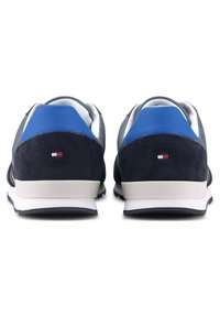 Baskets bleu marine en cuir et daim, avec une semelle blanche, un renfort de talon bleu et un petit logo à l'arrière.