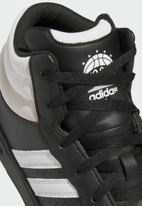 Czarno-białe trampki typu high-top z cholewką wykonaną z skóry i siateczki, trzema białymi pasek oraz logo adidas na języku.