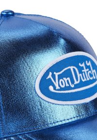 Blue metallic baseball cap with smooth texture. Features white embroidered logo on a blue oval patch. Curved brim and snapback closure.
