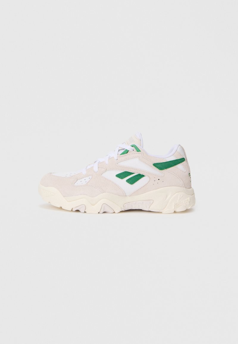 Sneakers w beżowym zamszu i białej siateczce, z zielonymi akcentami i teksturowaną podeszwą. Posiadają sznurowany przód i wyściełany kołnierz.