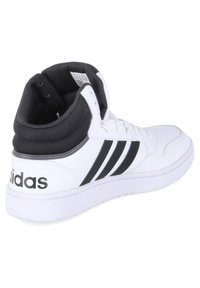 Hvide højtop sneakers med sorte accenter. Fremstillet af syntetisk materiale. Har tre sorte striber og en polstret krave. Gummisål.