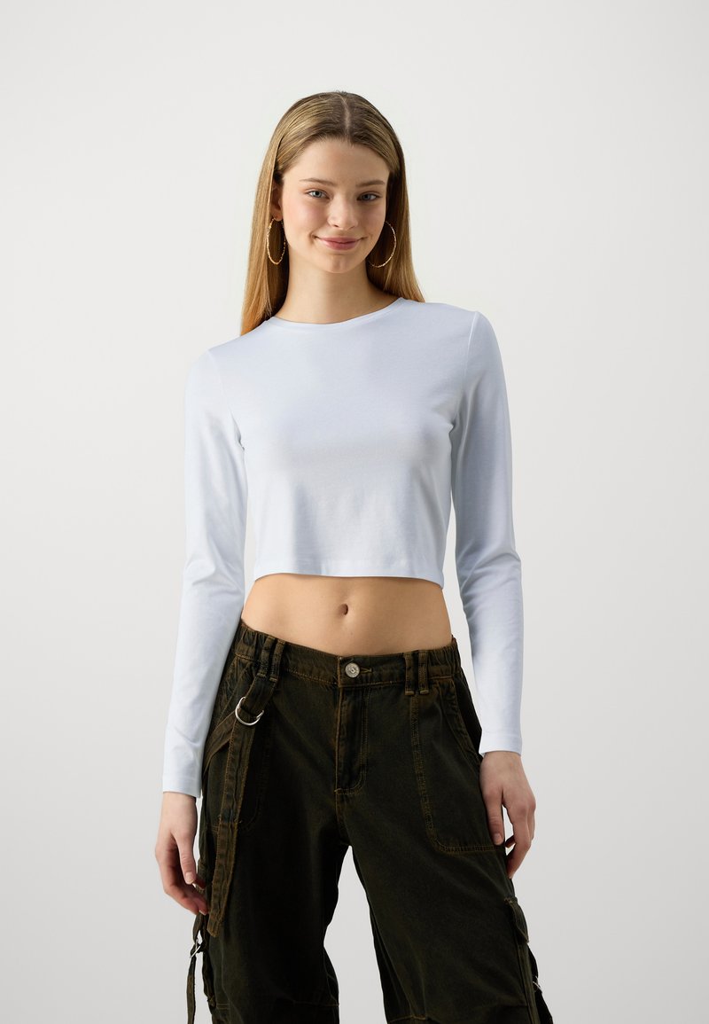 Lyseblå langermet crop-top kombinert med mørkegrønne cargo-bukser med sidelommer og detaljer i metallring.