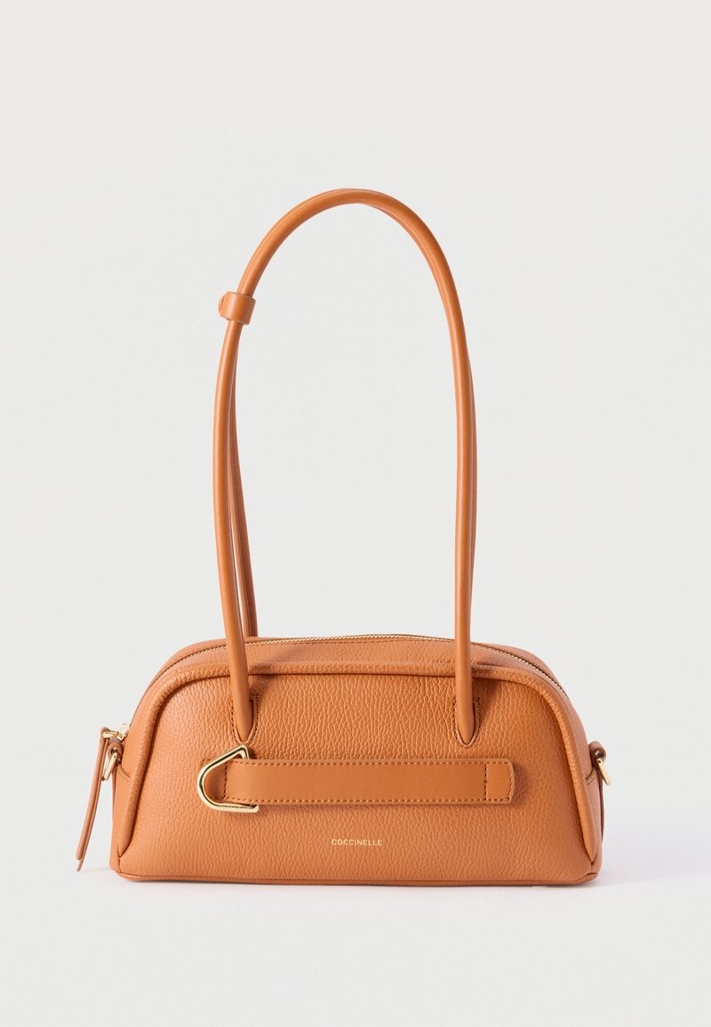 Τσάντα χειρός από δέρμα φυστικοβούτυρο με διπλές λαβές, λεπτομέρεια χρυσής αγκράφας και κλείσιμο με φερμουάρ, με το λογότυπο «Coccinelle» στο κέντρο της μπροστινής πλευράς.