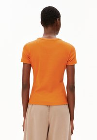 Korte oranje getailleerde t-shirt met een ronde halslijn en korte mouwen, gemaakt van ribstof, gezien vanaf de achterkant tegen een witte achtergrond.