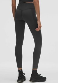 Zwarte hoge taille leggings gemaakt van rekbare stof, met een gladde textuur, aansluitende pasvorm en subtiele naaddetails langs de zijkanten.