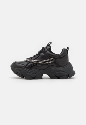 Czarny masywny sneaker z teksturowaną podeszwą, skórzana cholewka, srebrny detal łańcucha, czarne sznurówki oraz pętelki do ściągania na języku i pięcie.