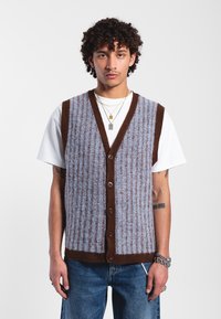 Gilet tricoté en bleu clair et marron, avec un col en V, une fermeture par boutons, une texture côtelée et un motif à rayures verticales.