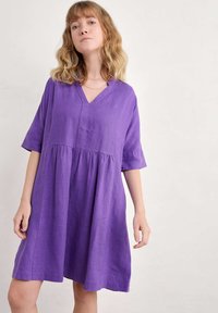 Violetti, polvipituinen mekko, joka on valmistettu kevyestä kankaasta. Siinä on V-pääntie, lyhyet hihat ja kerätty vyötärö, joka luo rentoa siluettia.