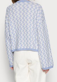 Maglione all'uncinetto in un motivo zigzag blu chiaro e bianco, con collo a coste e maniche larghe e oversize. Orlo cropped.