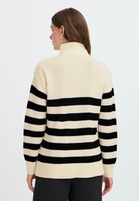 Maglione a collo alto a righe bianco e nero con una texture a coste e vestibilità comoda, dotato di maniche lunghe e scollatura alta.