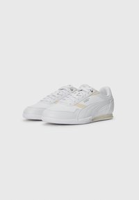 Chaussures de sport blanches en cuir et matériaux synthétiques, avec des semelles en caoutchouc texturé, des surfaces lisses et de subtils accents de branding.