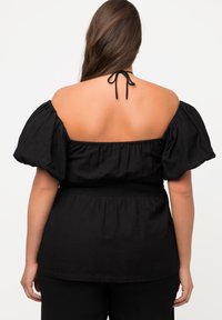 Sort off-the-shoulder top med puffærmer, smocket talje og bindebånd i nakken. Blødt, struktureret stof.