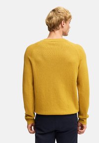 Musztardowy żółty sweter z dzianiny z okrągłym dekoltem, ściągaczami i bezszwowym krojem ramion. Miękka tekstura i luźny fason.
