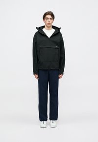 Μαύρο πουλόβερ μπουφάν με κουκούλα, τσέπη μ�προστά με φερμουάρ και κορδόνι στο στρίφωμα, συνδυασμένο με ναυτικές παντελόνες και λευκά αθλητικά παπούτσια. Απλός σχεδιασμός.