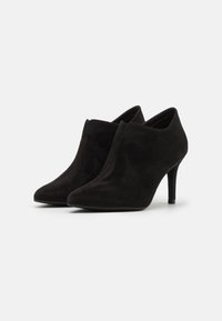 Botines de ante negros de tacón alto, con punta afilada y una textura suave, que presentan un diseño sin cremalleras y una silueta minimalista.