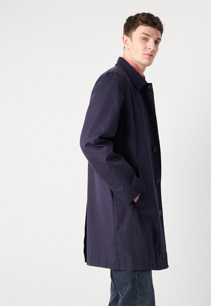 Granatowy, długi płaszcz przeciwdeszczowy o prostym kroju, zapinany na guziki z przodu, z bocznymi kieszeniami. Wykonany z gładkiego, wodoodpornego materiału.